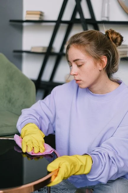 Anonymous person in yellow rubber gloves using simple sponge for cleaning mirror in bathroom